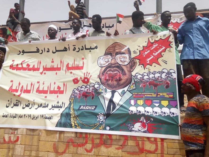 معتصمون أمام القيادة العامة للجيش السوداني يرفعون صورة للرئيس المخلوع عمر البشير . 19 أبريل 2019