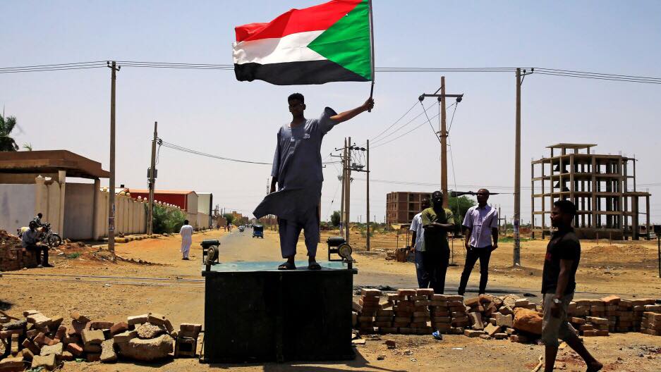 متظاهر سوداني يحمل العلم الوطني وهو يقف على حاجز في الطريق ، يطالب المجلس العسكري الانتقالي في البلاد بتسليم السلطة إلى المدنيين ، في الخرطوم ، السودان ، 5 يونيو 2019. (رويترز)