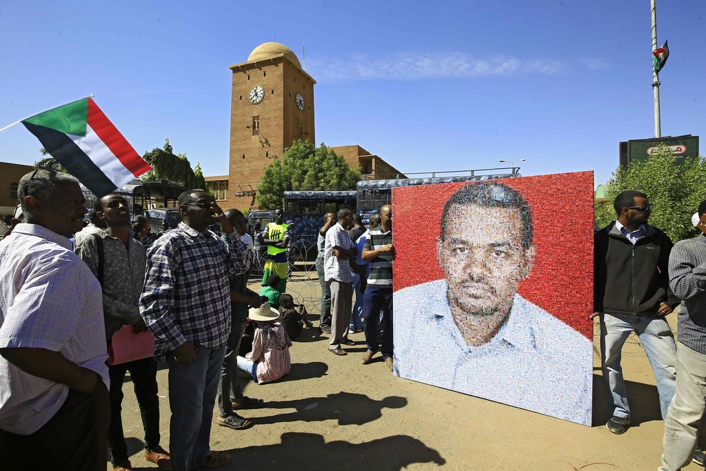 متظاهرون مع صورة للمعلم أحمد الخير خارج محكمة في أم درمان ، السودان ، يوم الاثنين/ وكالة الصحافة الفرنسية